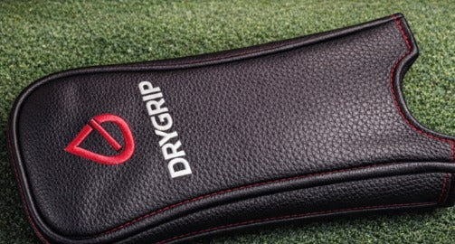 Black DryGrip™ golf grip cover with red trim on golf course turf